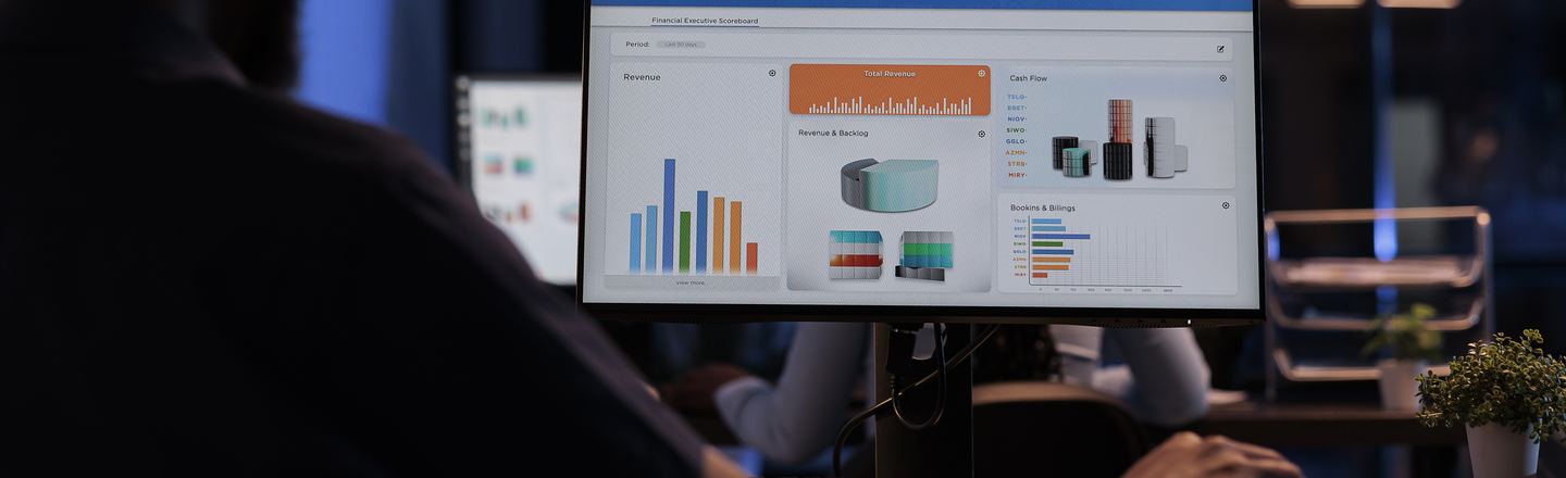 Over a colleague's shoulder: a financial performance dashboard on screen.
